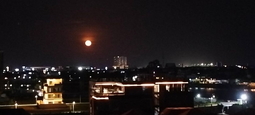 A photo of the moon rising over Phnom Penh looking bigger and more lustrous than usual. It is the Moon Illusion when the moon appears many times its usual size when close to the horizon. Taken 11 July 2025.